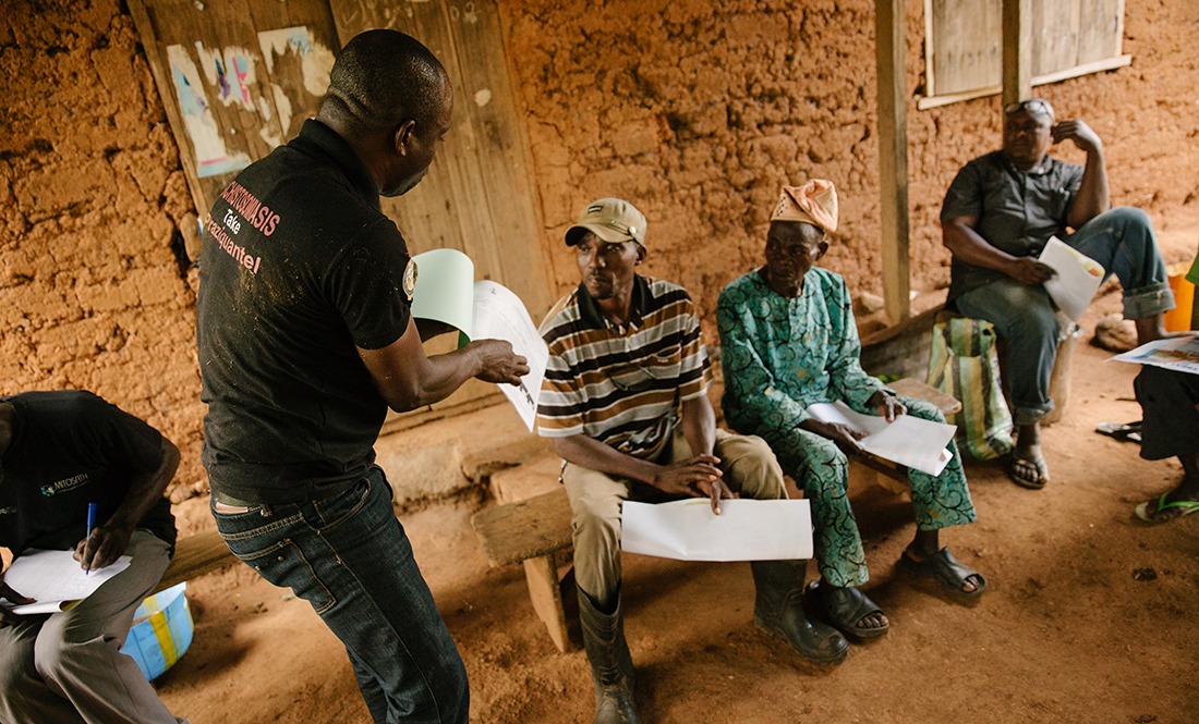 A worker talks with locals about river blindness treatment.