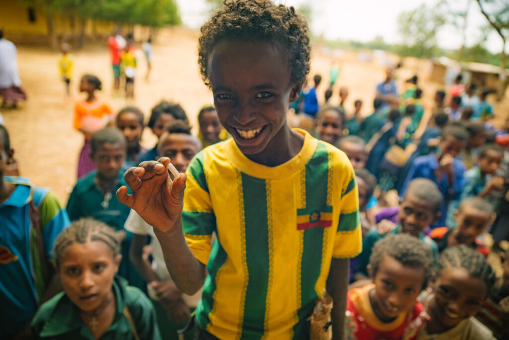 Child smiling and holding a pill in Ethiopia.