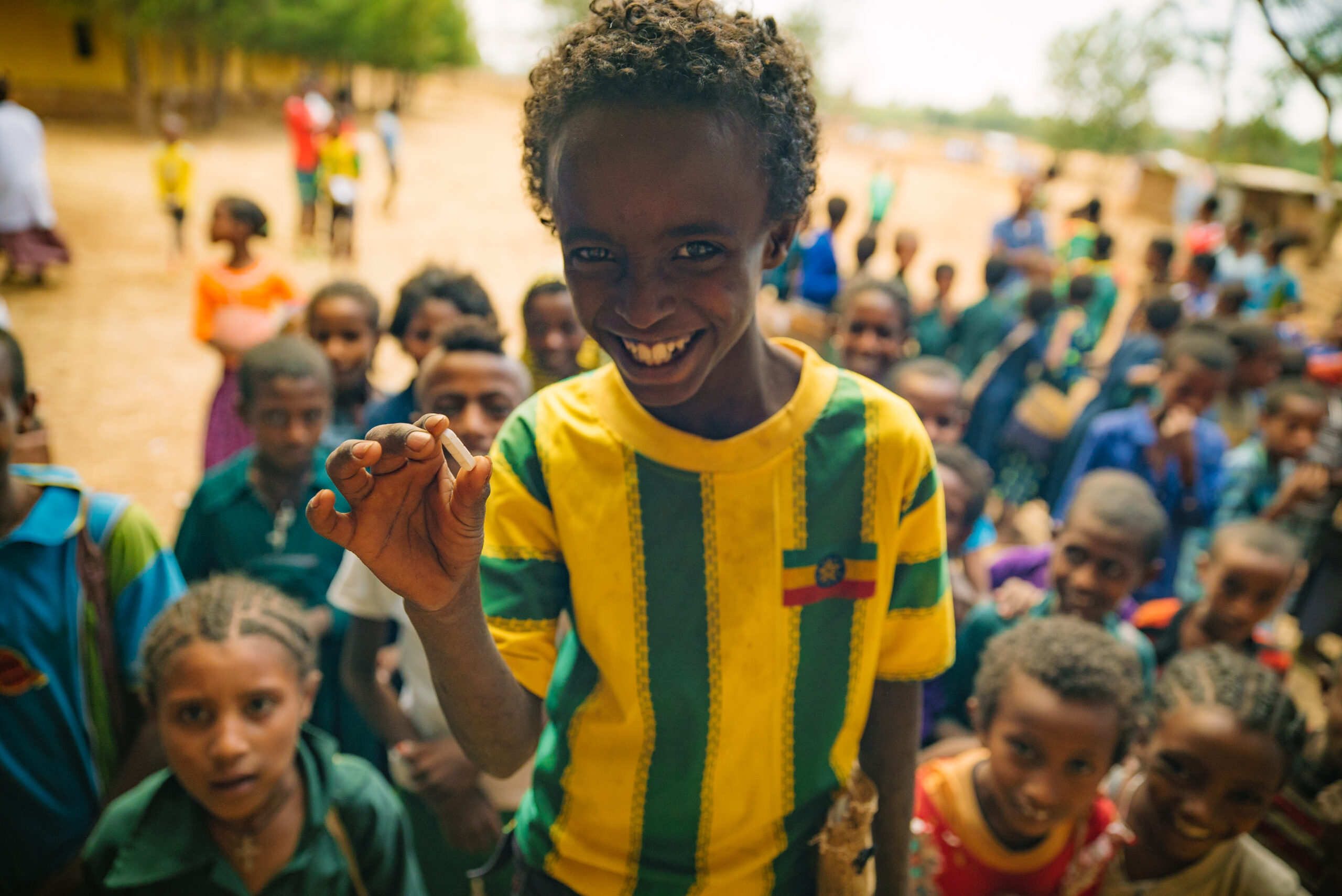 Child smiling and holding a pill in Ethiopia.