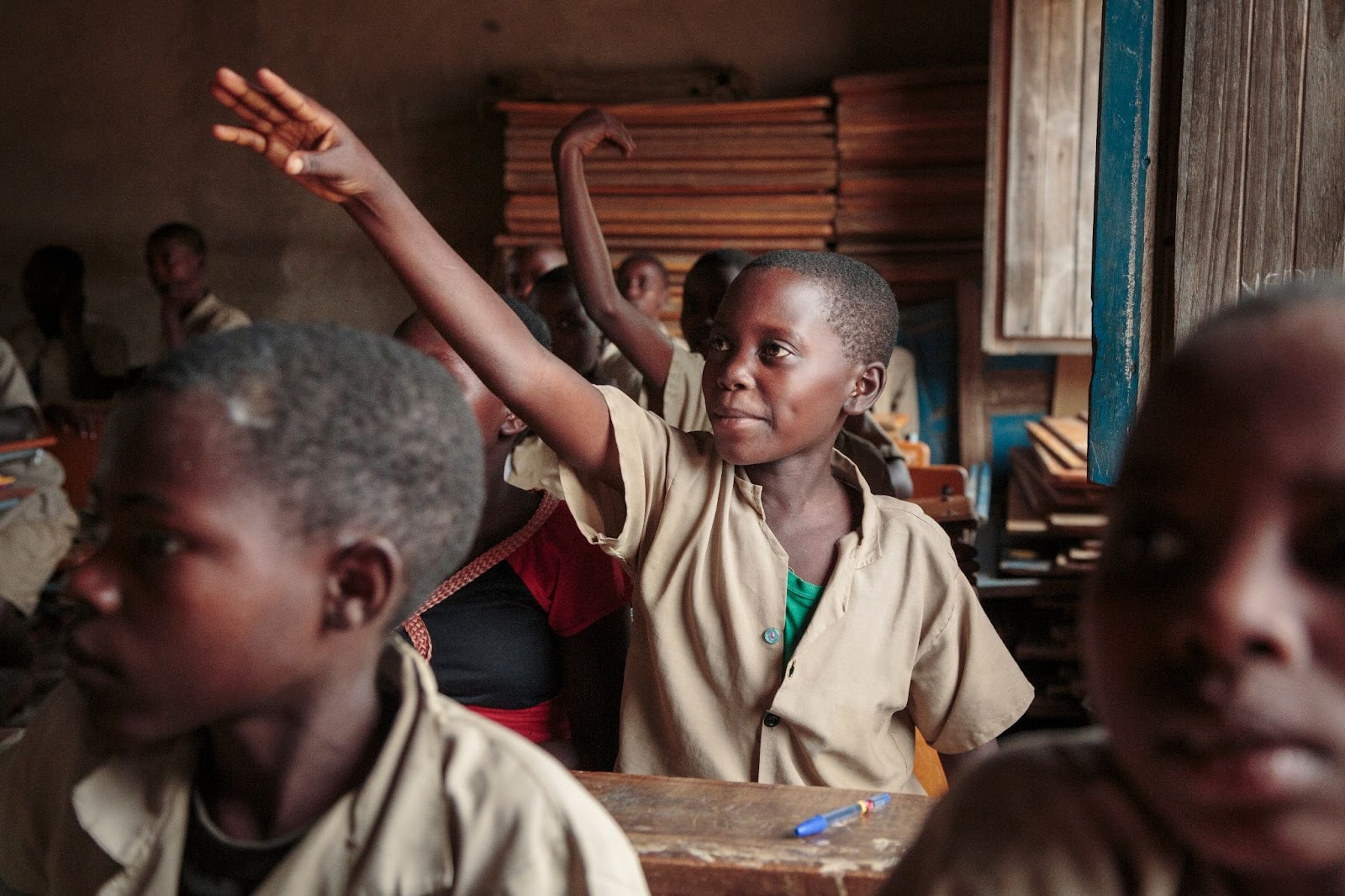 Student raises hand in classroom demonstrating educational outreach component of END Fund Burundi impact on community health awareness
