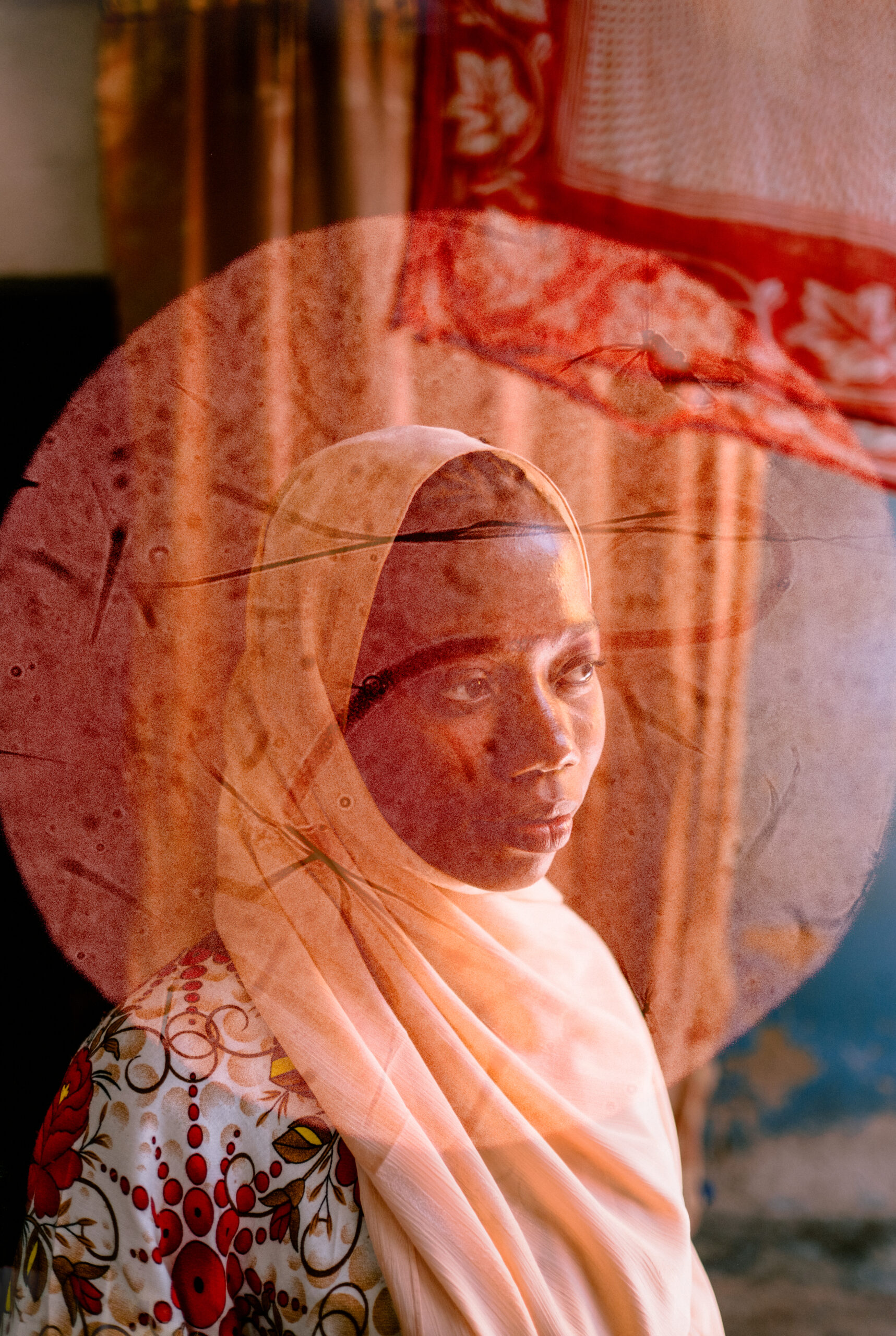 Suliya sits in her home. The photo is double exposed with images from a microscope that show the parasitic worms that cause VL